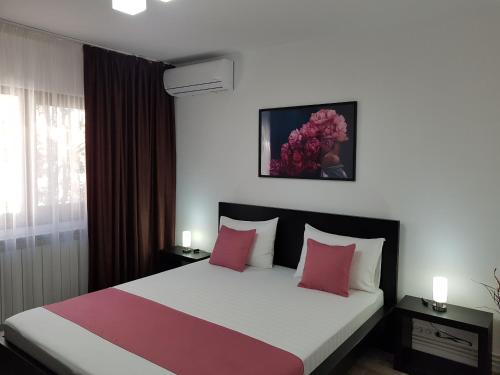 a bedroom with a large bed with pink pillows at Mary Apartment in Galaţi
