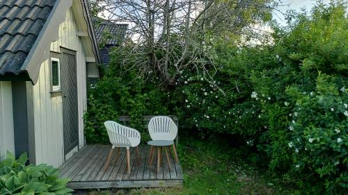 two chairs and a table on a wooden deck at Lilla mysstuga i havsnära in Varberg