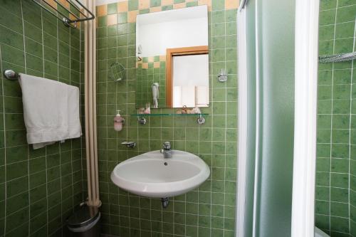 a green tiled bathroom with a sink and a mirror at Hotel Plaza in Rimini