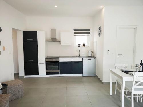 a kitchen with black and white appliances and a table at Island Cottage Apartment in Božava