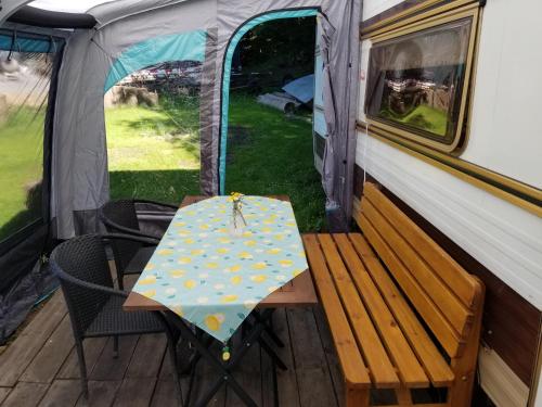 einen Tisch und Stühle auf der Veranda eines Zeltes in der Unterkunft Sykovec Karavan Sýkorka in Nové Město na Moravě