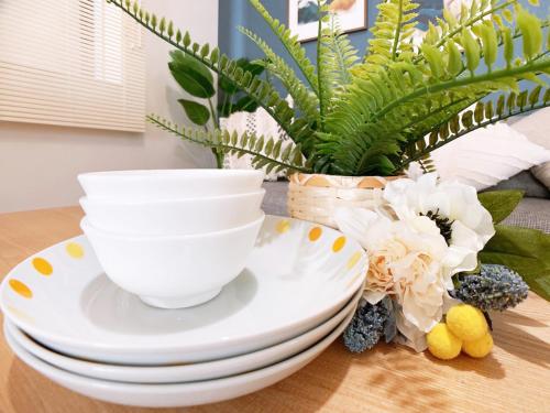 a table with plates and a bowl and a plant at OUCHI HOTEL Hijiyama in Hiroshima