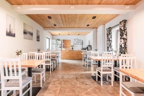 a restaurant with wooden ceilings and tables and chairs at Nowe Izby in Szaflary