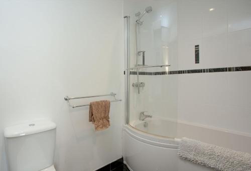 Un baño blanco con ducha y WC. en Waterview House, Kingswear, en Kingswear