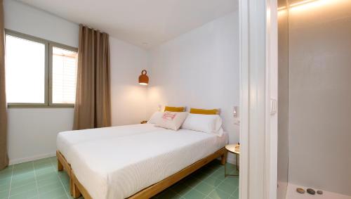 a bedroom with a large white bed and a window at Hostal Boutique Cana Rita in San Antonio