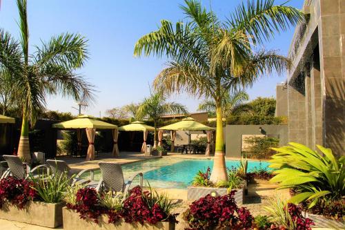 a swimming pool with palm trees and umbrellas at Urban Bliss Hotel in Kabwe