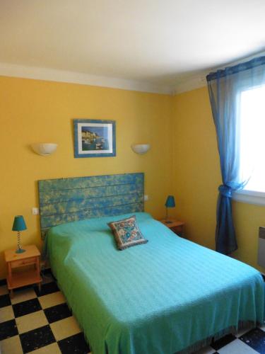 une chambre avec un lit avec un couvre-lit bleu dans l'établissement La Luciole, à Canet