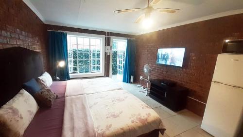 a bedroom with a large bed with a ceiling fan at Cozy Hatfield Condo in Pretoria