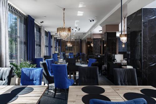 un restaurante con sillas azules, mesas y ventanas en Hotel Cristal Park, en Tarnów