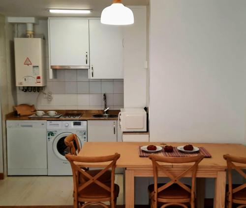 y cocina con mesa de madera, sillas y fogones. en Apartamento en Reina Victoria en Santander