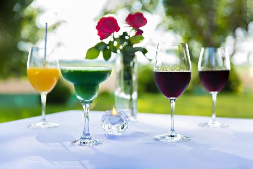 Quatre verres à vin sur une table avec un vase de roses dans l'établissement Mazurski Diament koło Mrągowa, à Sorkwity