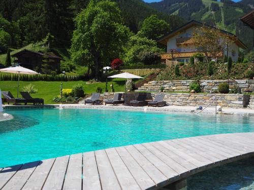 a large swimming pool with chairs and a house at Boutique Hotel Martha in Zell am See