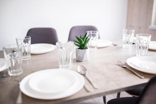 a wooden table with white plates and glasses and a plant at Silva in Rewal