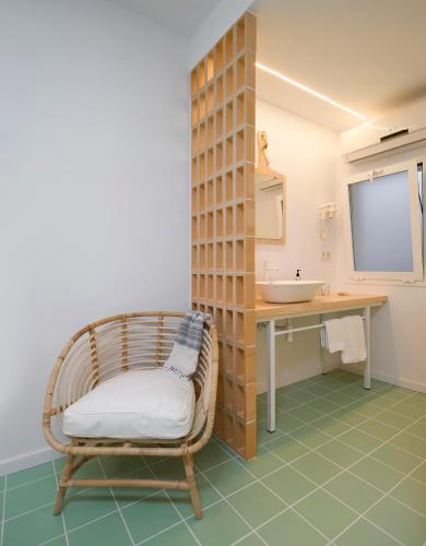 a bathroom with a rattan chair and a sink at Hostal Boutique Cana Rita in San Antonio