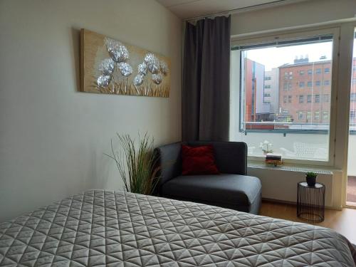um quarto com uma cama, uma cadeira e uma janela em Lutakko Apartment 2 with free car parking em Jyväskylä