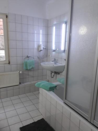 een witte badkamer met een wastafel en een bad bij Ferienwohnung Steinweg 28 in Quedlinburg