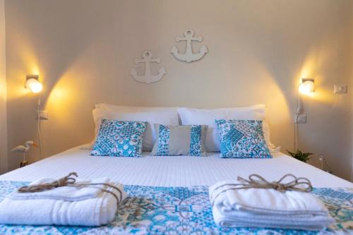 a bedroom with a large bed with blue and white pillows at Villa Curiazzi Guesthouse Viale la Pelosa 16 in Stintino