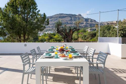 a white table with chairs and food on it at VILLA IRIS in PEFKOS, PINE VILLAS in Pefki Rhodes