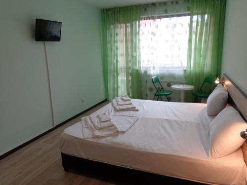 a bedroom with a bed with white sheets and a window at Къща за гости А. Б. В. in Nesebar