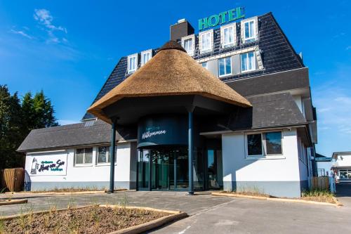 a hotel building with a thatched roof at Stratmanns Haus am See in Lembruch
