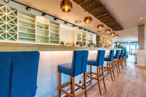a bar with blue chairs at a restaurant at Stratmanns Haus am See in Lembruch