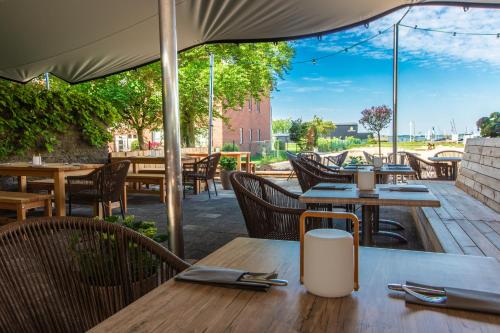 an outdoor patio with tables and chairs and an umbrella at Stratmanns Haus am See in Lembruch