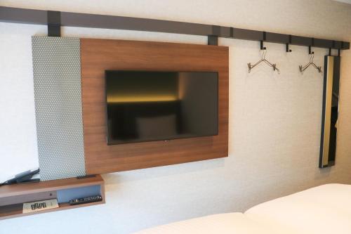 a flat screen tv hanging on a wall with two hangers at Hotel The M's Kyoto in Kyoto