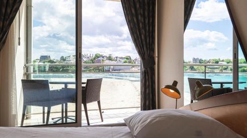 a bedroom with a bed and a view of a balcony at Le Crystal Dinard Plage in Dinard