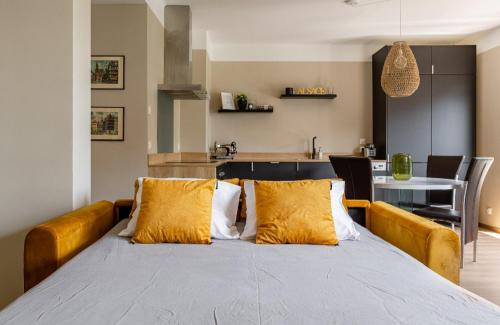 uma cama grande com almofadas amarelas num quarto em L'austerlitz, T2 au coeur de Strasbourg em Estrasburgo