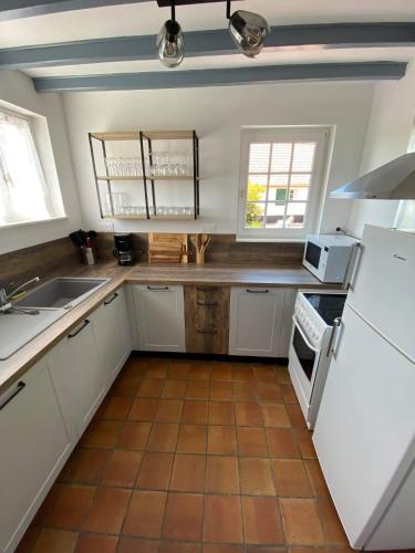 une cuisine avec des armoires blanches et un sol carrelé dans l'établissement Cottage Lucas, à Rue