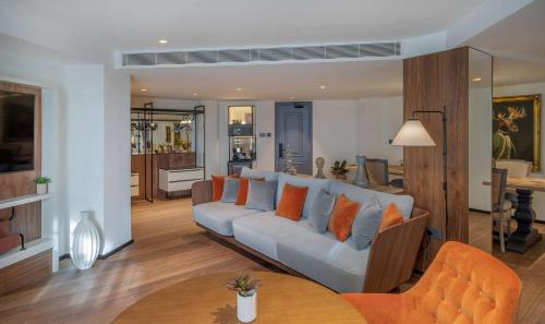 a living room with a couch with orange pillows at Melia White House Hotel in London