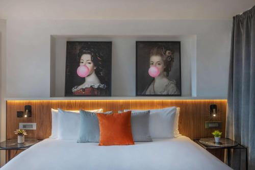 a bedroom with a bed with two pictures on the wall at The Level at Melia White House in London