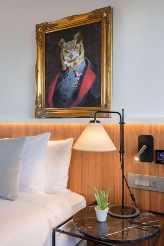 a painting of an owl in a suit next to a bed at The Level at Melia White House in London