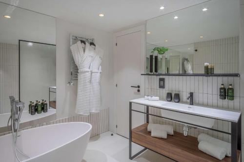 a white bathroom with a tub and a sink at The Level at Melia White House in London