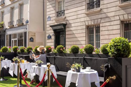 a woman sitting at a table in front of a building at Hôtel Vinci Due & Spa in Paris