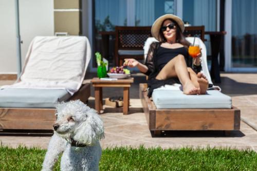 a woman sitting in a chair with a white dog at SPA Villa - Sunny Villas Hanioti in Hanioti