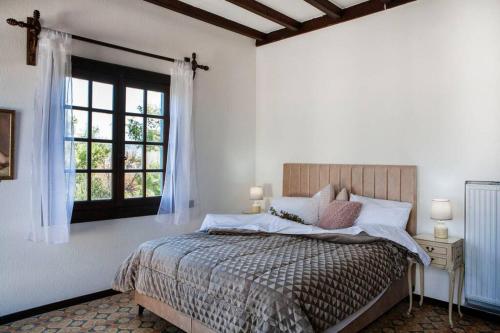 a white bedroom with a bed and a window at Villa Velissarios: wonderful villa next to beach in Egina