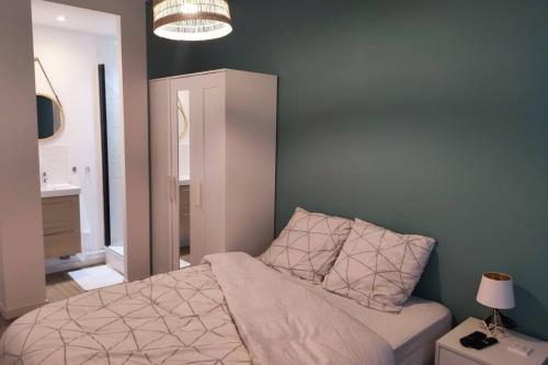 1 dormitorio con 1 cama con mesita de noche y lámpara en Appartement 3 chambres, 3 salles d'eau, en Saint-Herblain