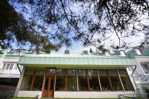 a building with a green roof with glass windows at Panorama Hotel Noszvaj in Noszvaj