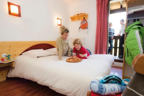 two children sitting on a bed with a plate of food at VTF Le Dou De La Ramaz in Montalbert