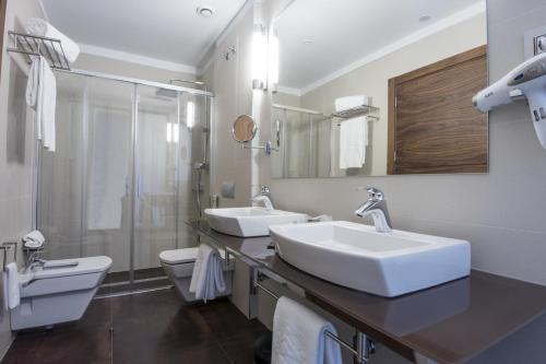a bathroom with two sinks and a toilet and a shower at Parador de Lleida in Lleida