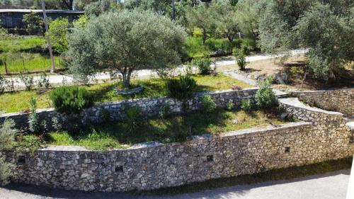 a garden with trees and a stone wall at Irida in Lefkada Town