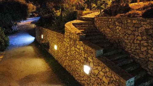 a stone wall with stairs and lights at night at Irida in Lefkada Town