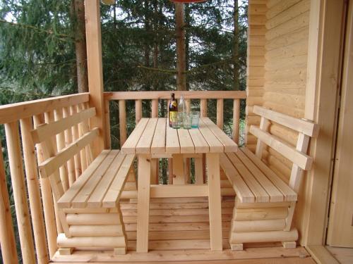 una mesa de madera y un banco en el porche de una cabaña en Baumhaus Hotel Voglsam, en Schönau