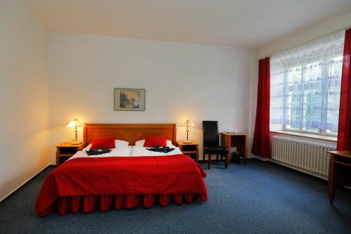 a hotel room with a red bed with red curtains at Hotel Magnolia in Roudnice nad Labem