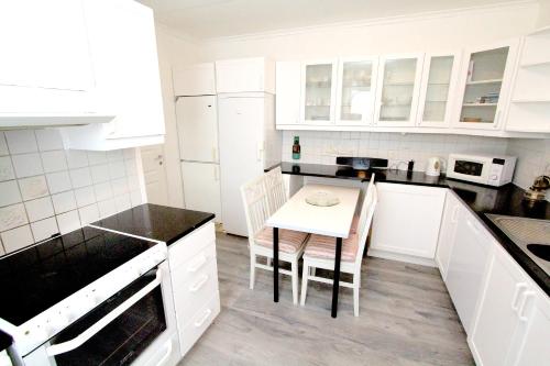 una cocina con armarios blancos y una mesa pequeña. en Tallkrogen Romantic House - Upper or Lower Apartment, en Estocolmo