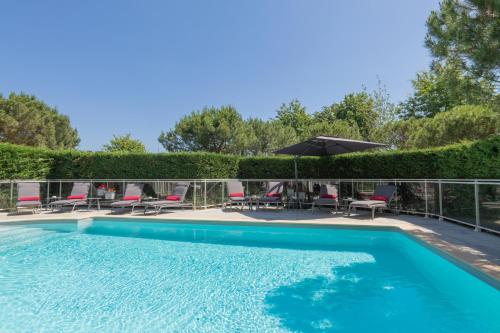 - une piscine avec des chaises et un parasol dans l'établissement Le M & Spa by Hôtels & Préférence, à Mérignac