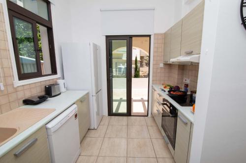 eine Küche mit weißen Arbeitsplatten und einer Tür zu einer Terrasse in der Unterkunft Mylos 9 in Protaras