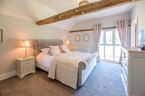 a bedroom with a bed and a large window at Chapel Cottage at Pond Hall Farm, Stunnning Property with Private Hot Tub in Ipswich