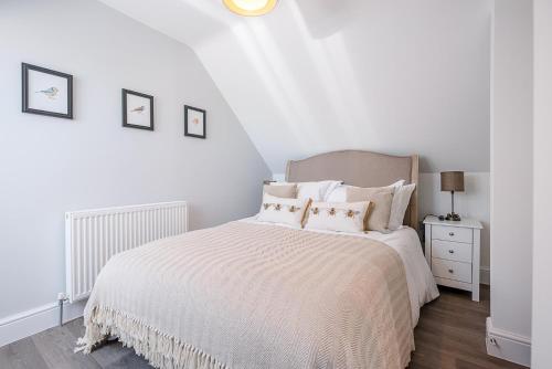 Dormitorio blanco con cama con sábanas y almohadas blancas en Geoff's Rest at Pond Hall Farm in Hadleigh with Private Hot Tub, en Ipswich